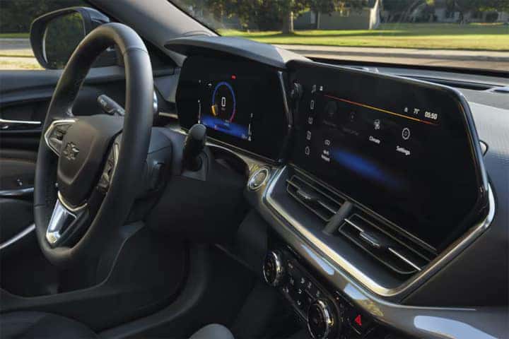 The image shows the interior of a modern car, featuring a steering wheel, a digital dashboard, and a large touchscreen display on the center console. The display shows various controls and settings. The car has a sleek, black design.