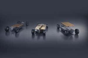 Three electric skateboard chassis with battery packs are displayed on a reflective surface. Each has a distinct configuration, showcasing various layouts. The background is a smooth gradient, emphasizing the sleek and modern design of the chassis.