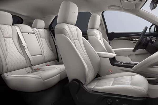 Car interior with white quilted leather seats, featuring front and rear seating areas. The design includes a modern center console, window accents, and headrests, providing a luxurious and spacious feel.
