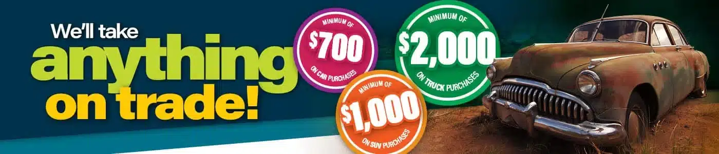 Trade-in promotion banner with old car offers up to $2,000 on truck purchases and $700 on cars.