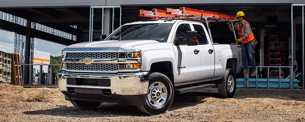 Chevrolet trucks parked at a construction site, featuring workers and a partially-built structure.
