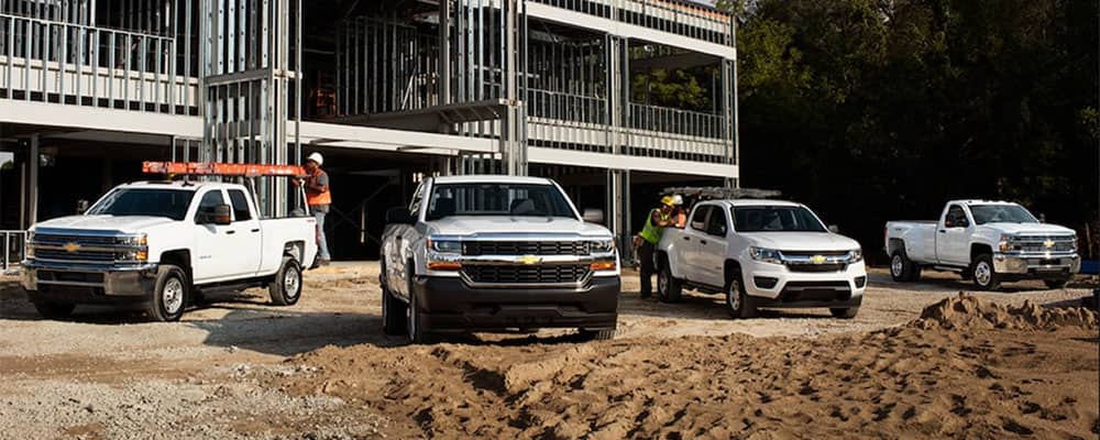 Chevrolet trucks parked at a construction site, featuring workers and a partially-built structure.