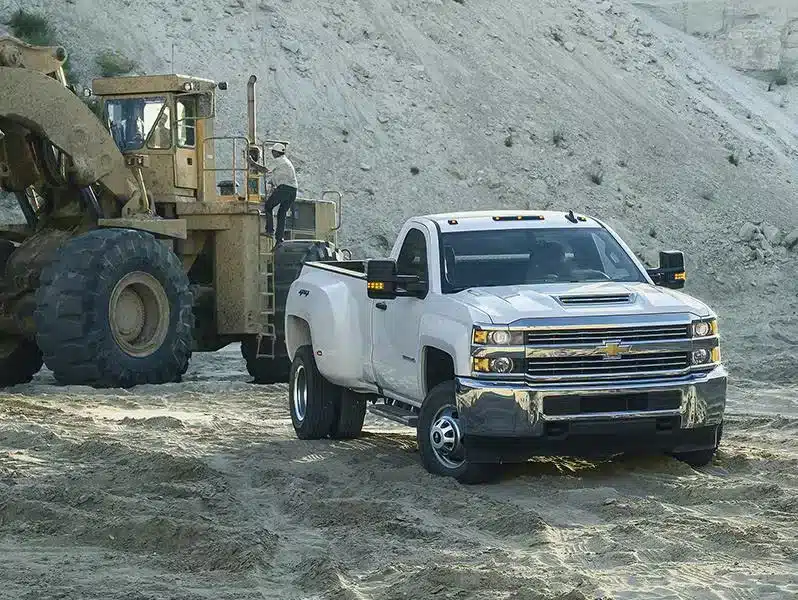 Forklift loading supplies onto a white pickup truck at a lumber yard, showcasing efficient material handling.