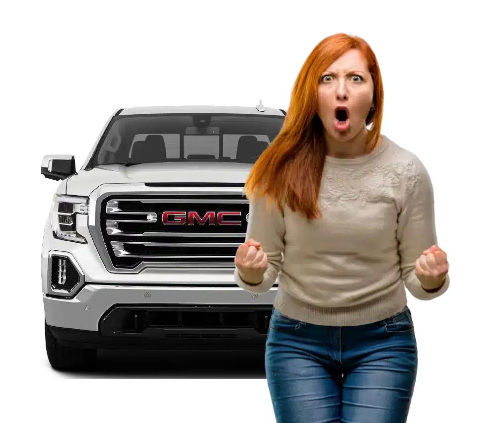 A redheaded woman with an expressive face stands in front of a white GMC truck.