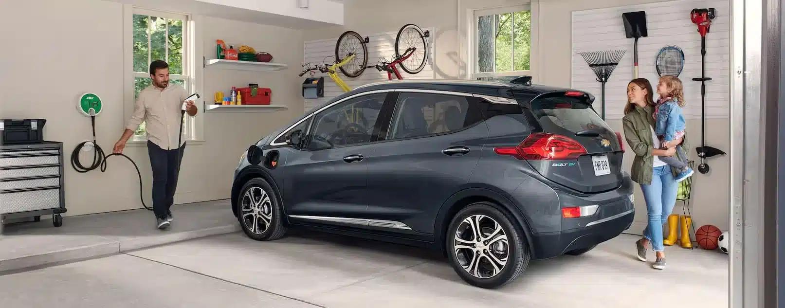 Family with an electric car in a garage, man plugging in a charger. Eco-friendly vehicle charging.