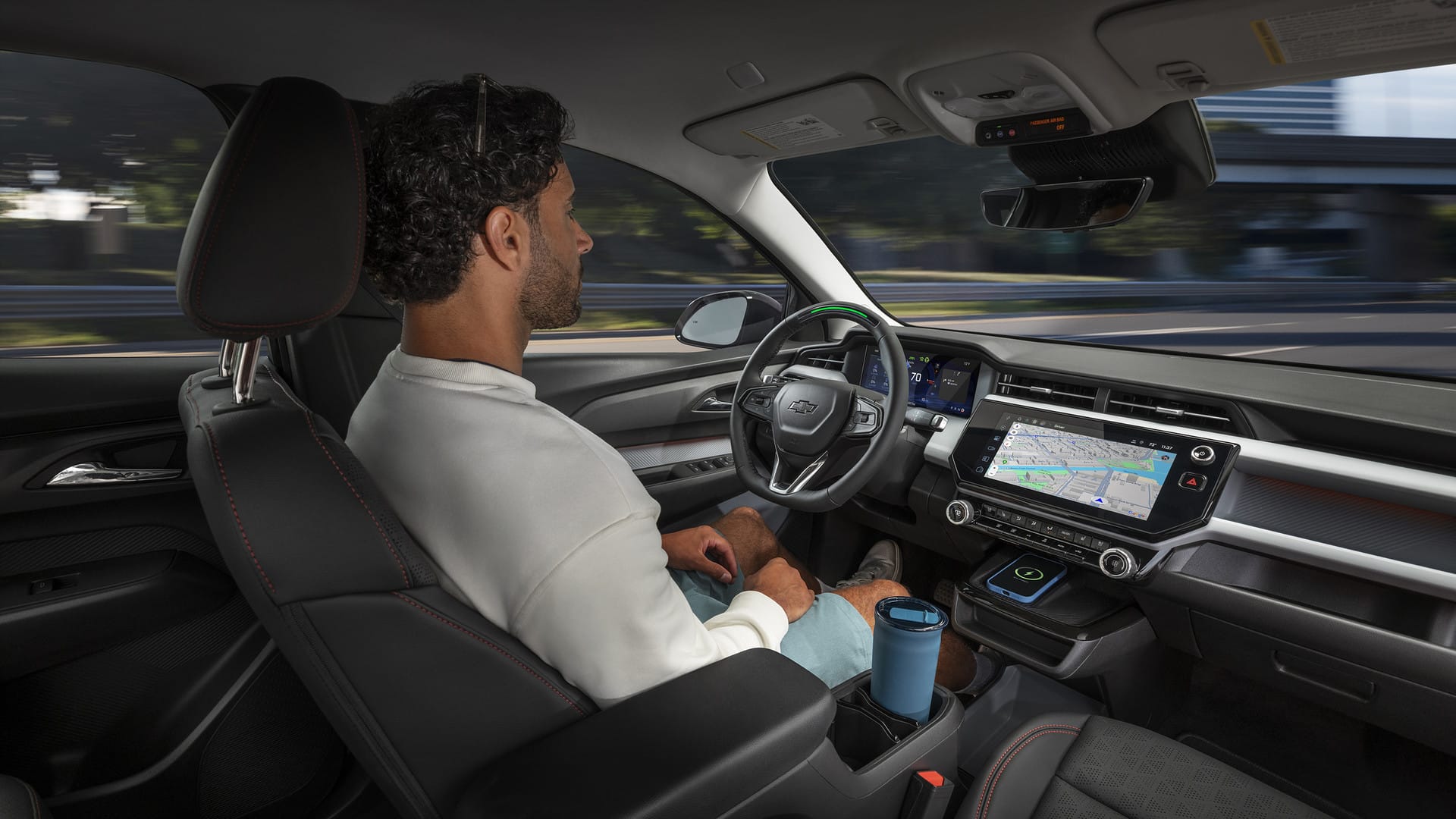 Person sitting in a car using autonomous driving, with maps on the dashboard display.
