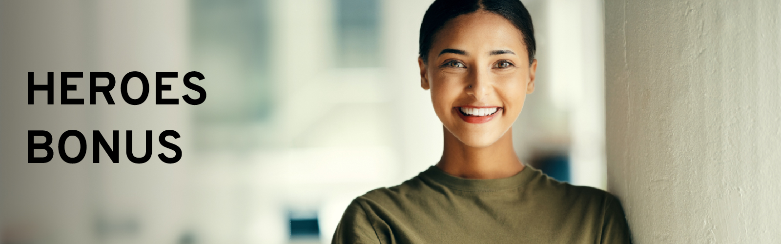Smiling person standing indoors with text "HEROES BONUS" to the left. Light background.