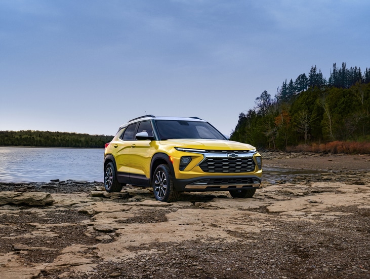 Red SUV with a sleek design parked indoors. The vehicle has prominent headlights and a bold front grille. The setting features a modern and spacious environment with architectural elements in the background.