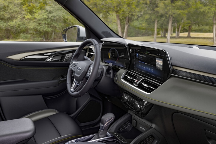 The image shows the interior of a modern car, featuring a steering wheel, a digital dashboard, and a large touchscreen display on the center console. The display shows various controls and settings. The car has a sleek, black design.