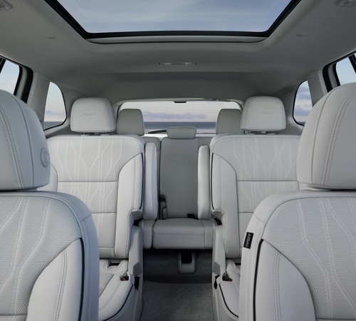Interior of a luxury SUV with white leather seats and a panoramic sunroof.