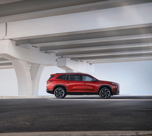 Red SUV parked beneath a modern overpass, showcasing sleek design and urban setting.