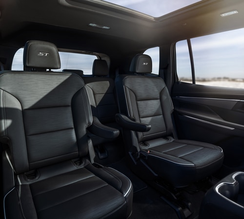 Luxury black leather interior of a modern SUV with captain seats and a panoramic sunroof.
