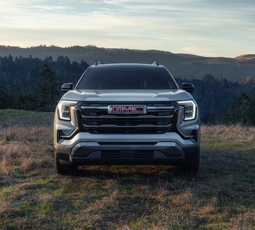 Front view of a GMC Sierra AT4 parked in a scenic outdoors setting with hills in the background.