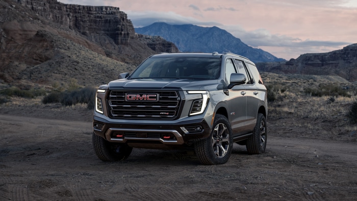 GMC SUV parked on a rugged terrain with mountainous backdrop at dusk.