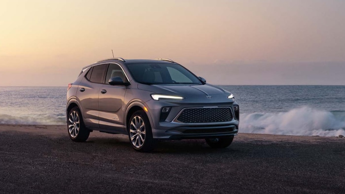 A sleek gray SUV parked by the ocean at sunset, showcasing modern design and LED headlights.